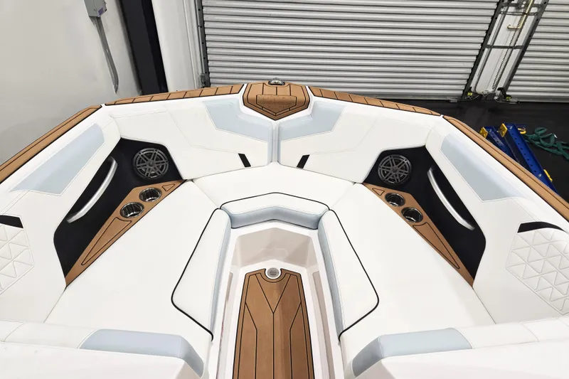 Slide: The Image of 2026 Nautique Super Air Nautique GS22 boat interior with white and tan seating, cup holders, and speakers. - 11