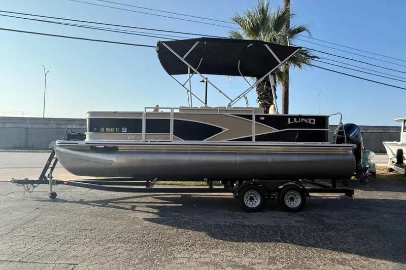 The Image of 2020 Lund LX220 Pontoon Fish boat on trailer, parked outdoors under clear sky. - 0