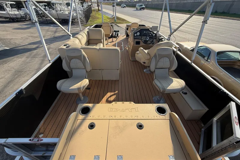 Slide: The Image of 2020 Lund LX220 Pontoon Fish boat interior with beige seating and wood-style flooring. - 12