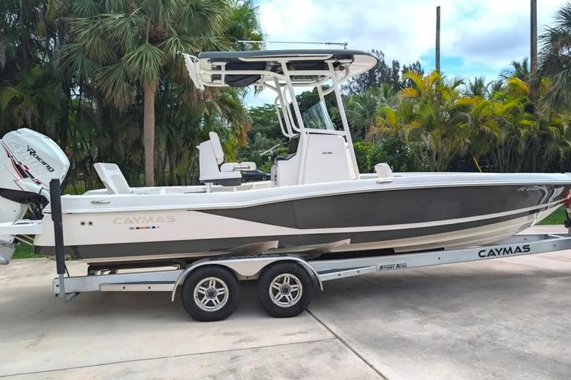 The Image of 2021 Caymas 26 HB boat on trailer, surrounded by tropical trees. - 0