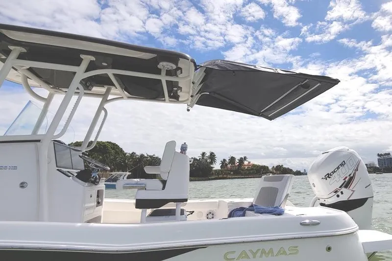 Slide: The Image of 2021 Caymas 26 HB boat with canopy, scenic water view, and outboard motor. - 3