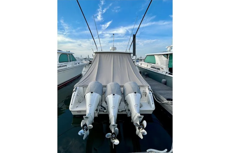 The Image of 2023 Pursuit OS 385 Offshore boat with triple outboard engines at a marina. - 0