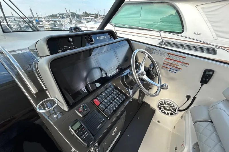 Slide: The Image of 2023 Pursuit OS 385 Offshore boat cockpit with modern steering and navigation controls. - 4