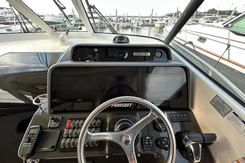 Slide: The Image of 2023 Pursuit OS 385 Offshore helm with advanced navigation controls and dual Garmin displays. - 5