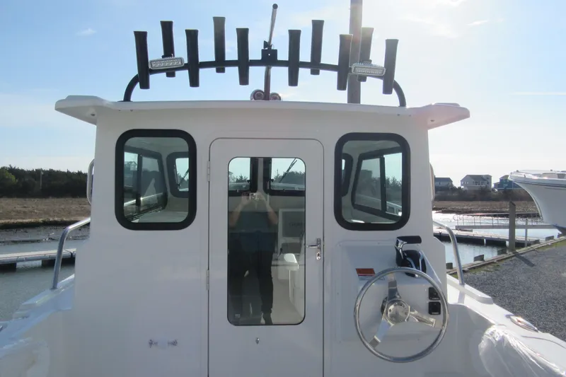 Slide: The Image of 2026 Parker 227 Explorer Sport Cabin boat at dock, featuring steering wheel and cabin windows. - 6