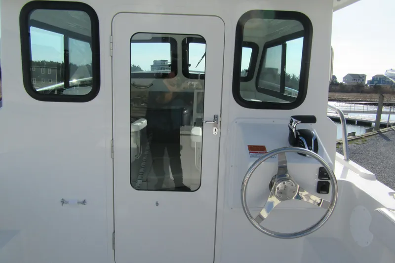 Slide: The Image of 2026 Parker 227 Explorer Sport Cabin boat with steering wheel and cabin door. - 8