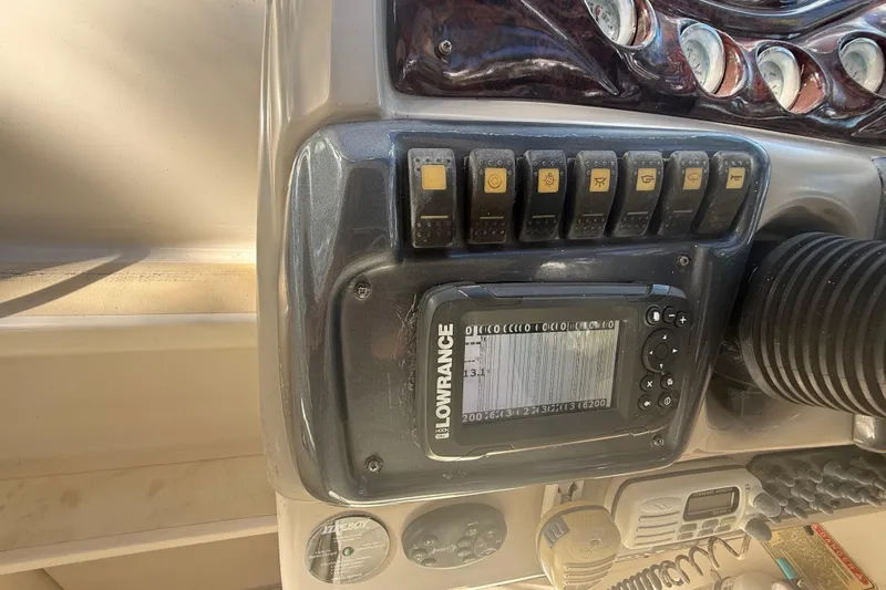 Slide: The Image of 2004 Monterey 265 Cruiser boat with open windshield and blue canopy, parked outdoors. - 43