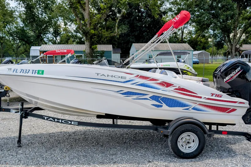 The Image of 2022 Tahoe T16 boat with vibrant graphics on a trailer, parked outdoors. - 1