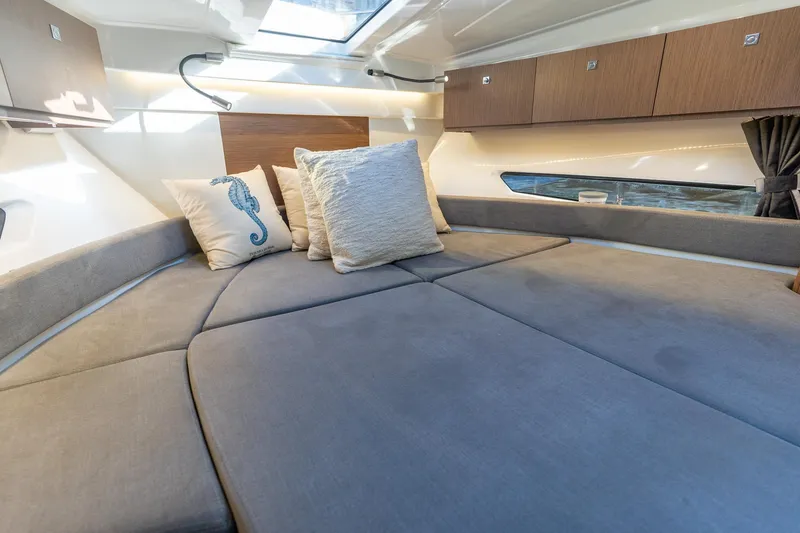 Slide: The Image of 2021 Beneteau Antares 9 cabin interior with cozy bedding and decorative pillows. - 13