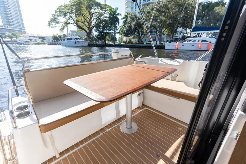 Slide: The Image of Beneteau Antares 9 (2021) boat deck with seating and table, docked by waterfront. - 18