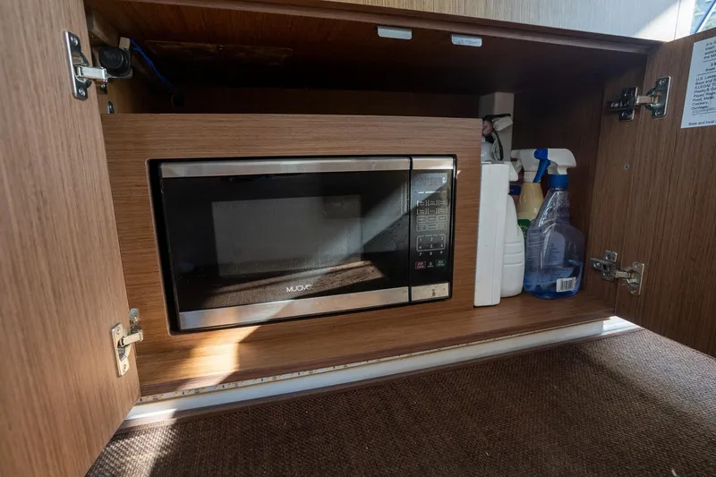 Slide: The Image of Microwave and cleaning supplies in Beneteau Antares 9, 2021 model cabinet. - 30