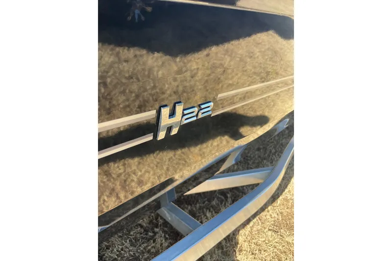 Slide: The Image of 2024 Express H22 emblem on sleek black surface, outdoor setting. - 14