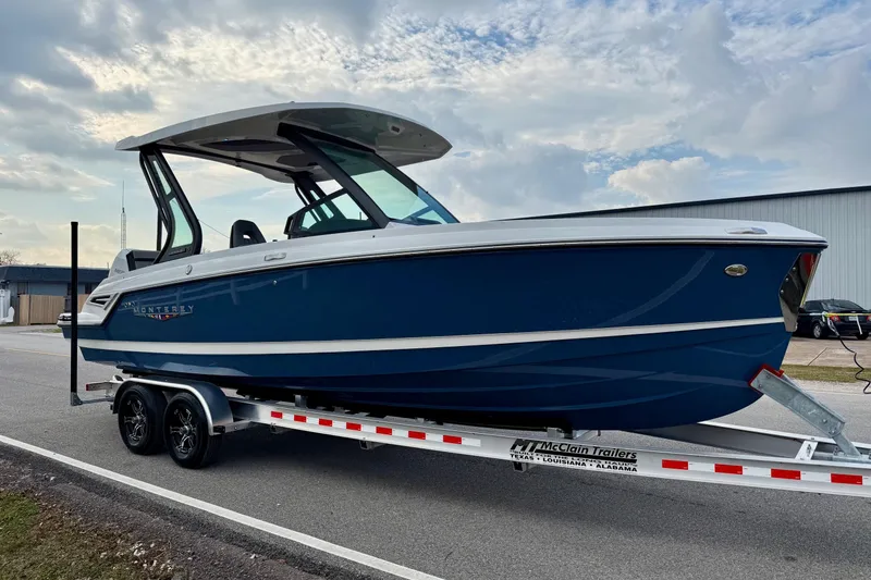 Slide: The Image of 2026 Monterey Elite 25 OB boat on trailer, blue hull, parked outdoors. - 5