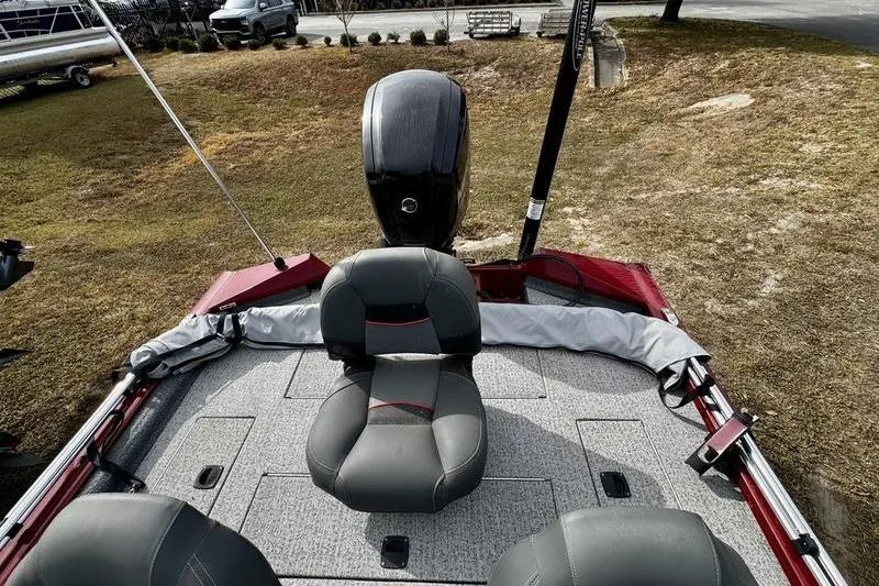 Slide: The Image of 2022 Tracker Pro Team 175 TXW boat interior with seating and motor, parked on grass. - 6