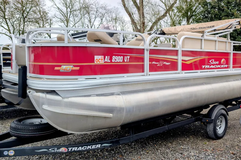 The Image of 2023 Sun Tracker Party Barge 18 pontoon boat on trailer, red and silver design. - 1