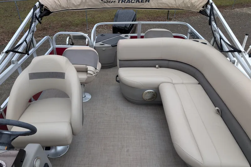 Slide: The Image of 2023 Sun Tracker Party Barge 18 interior with beige seating and steering console. - 6