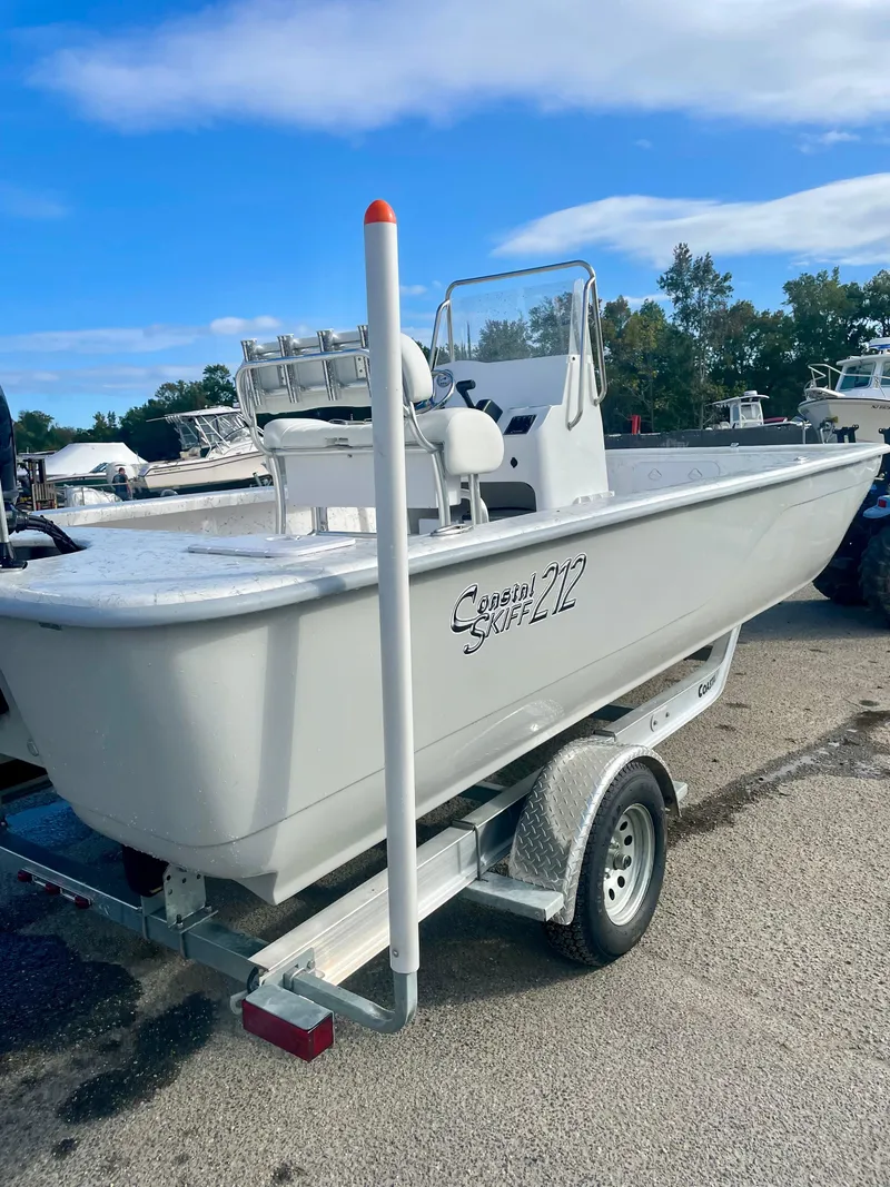 Slide: The Image of 2025 Coastal Skiff 212 boat on trailer, parked outdoors under blue sky. - 6