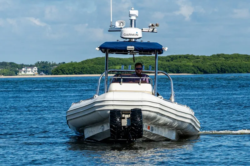 Slide: The Image of 2023 Ocean Craft 38 boat navigating calm waters with lush green shoreline. - 17