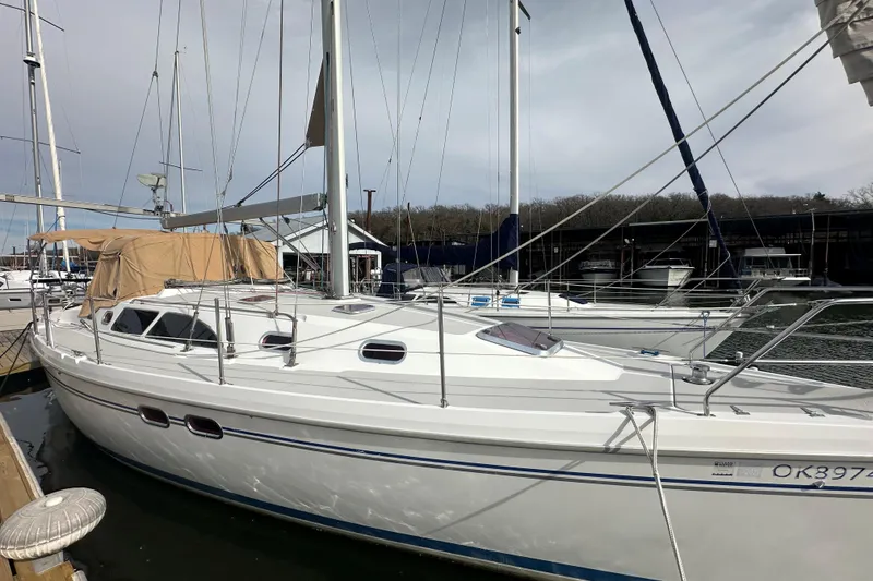 Slide: The Image of 2006 Catalina 387 sailboat docked at marina, featuring sleek white design and multiple windows. - 2