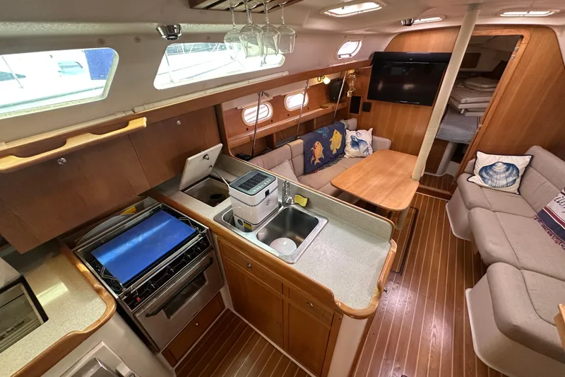 Slide: The Image of Interior of 2006 Catalina 387 sailboat with kitchen, seating, and wooden flooring. - 22