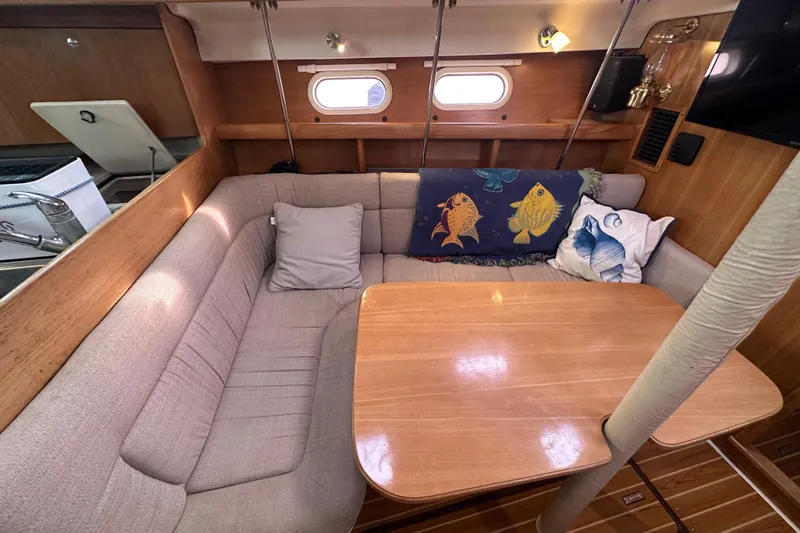 Slide: The Image of Cozy interior of a 2006 Catalina 387 sailboat with cushioned seating and decorative pillows. - 24