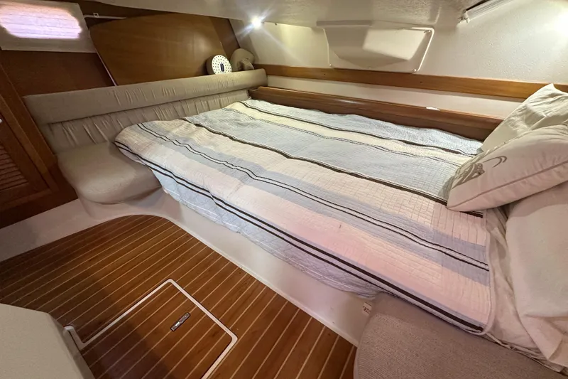 Slide: The Image of Cozy cabin interior of 2006 Catalina 387 sailboat with striped bedding and wooden flooring. - 38