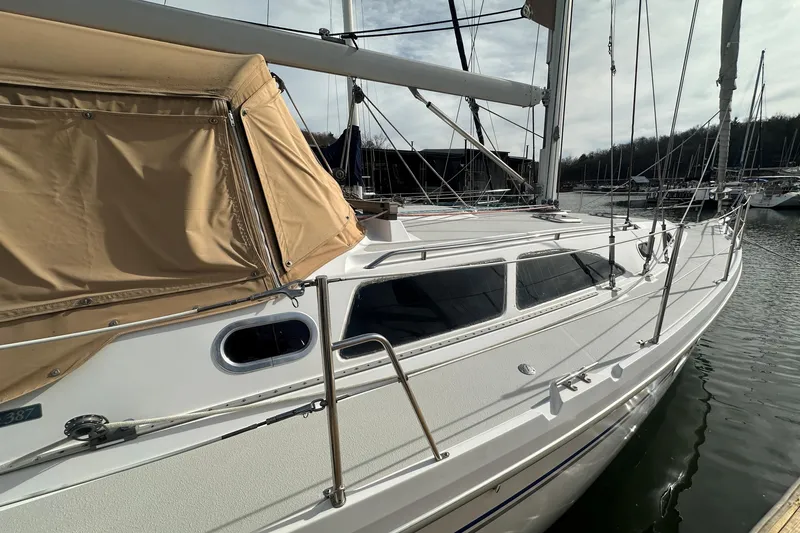 Slide: The Image of 2006 Catalina 387 sailboat docked, featuring beige canopy and sleek white deck design. - 4