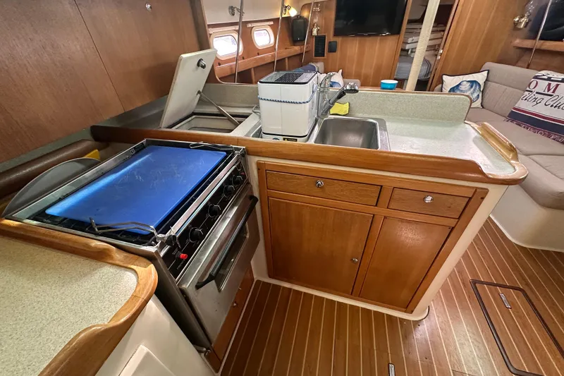 Slide: The Image of 2006 Catalina 387 yacht interior with kitchen, stove, sink, and seating area. - 49