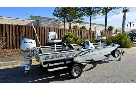 Slide: The Image of 2014 Alumacraft Pro 165 boat with Honda outboard motor, parked outdoors. - 2