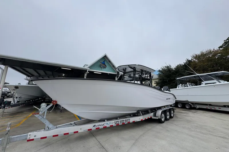 Slide: The Image of 2026 Cape Horn 32 XS boat on trailer, parked outdoors near other boats. - 3