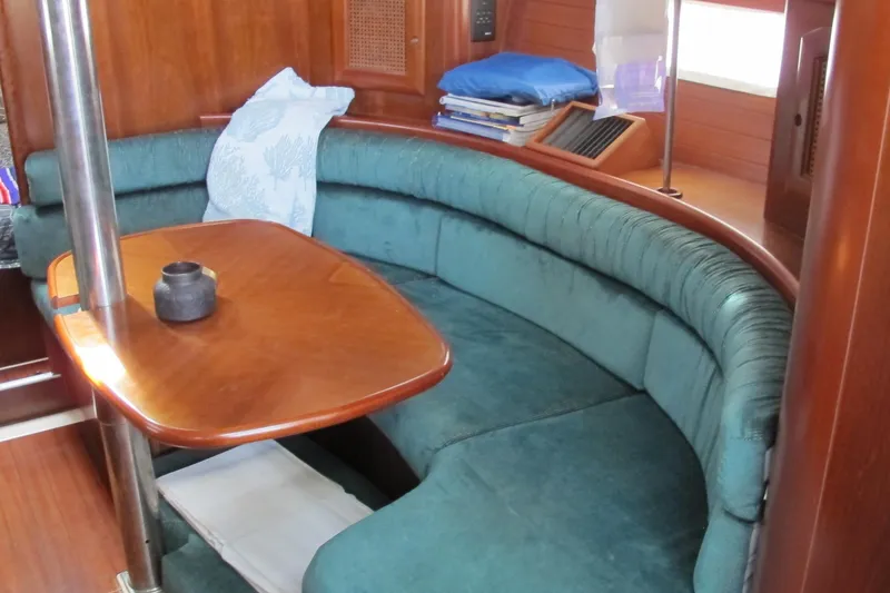Slide: The Image of Interior of 2000 Beneteau Oceanis 361 sailboat with curved seating and wooden table. - 26