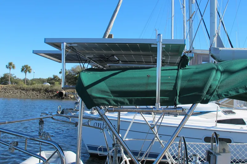 Slide: The Image of Beneteau Oceanis 361 sailboat with solar panels and green sail cover, docked by the water. - 7
