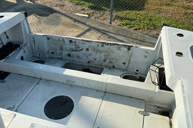 Slide: The Image of 2000 Boston Whaler Justice 24 boat interior, showing worn seating and storage compartments. - 11