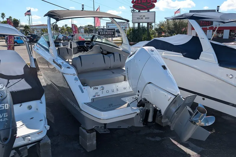 Slide: The Image of 2026 Four Winns H6 OB boat with outboard motor, displayed outdoors. - 2