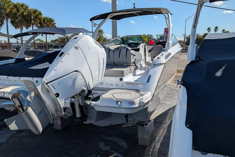 Slide: The Image of 2026 Four Winns H6 OB boat with outboard motor, parked outdoors under clear sky. - 3