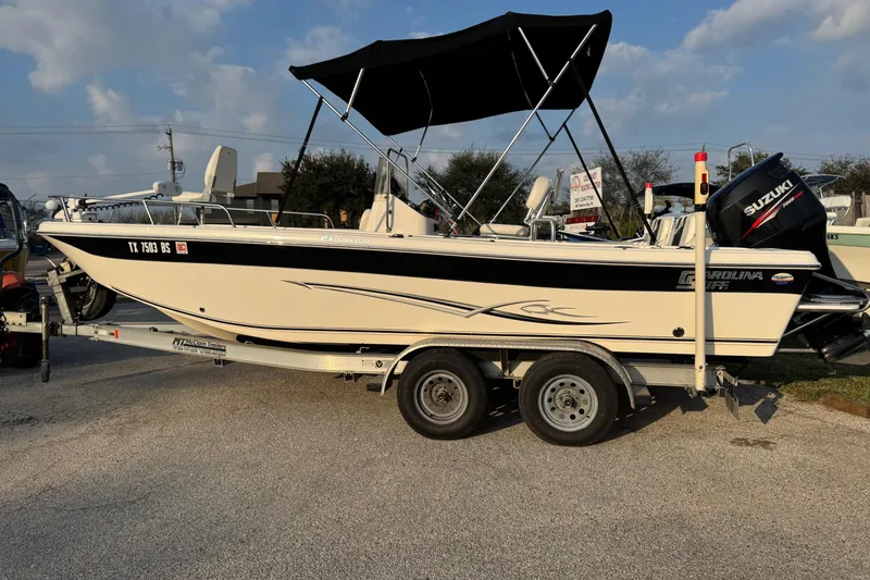 Slide: The Image of 2012 Carolina Skiff 21 Ultra Elite boat on trailer with Suzuki engine and canopy. - 17