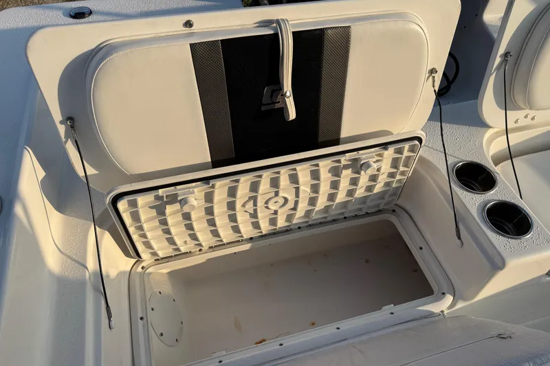 Slide: The Image of 2012 Carolina Skiff 21 Ultra Elite boat storage compartment with open lid and cup holders. - 4