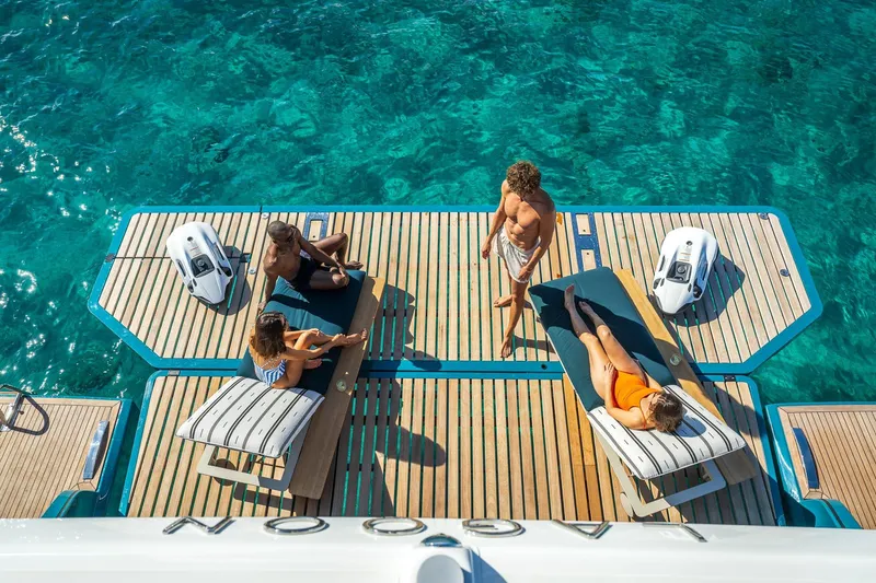 Slide: The Image of People relaxing on Lagoon Eighty 2 yacht deck, 2026, with clear blue water. - 14