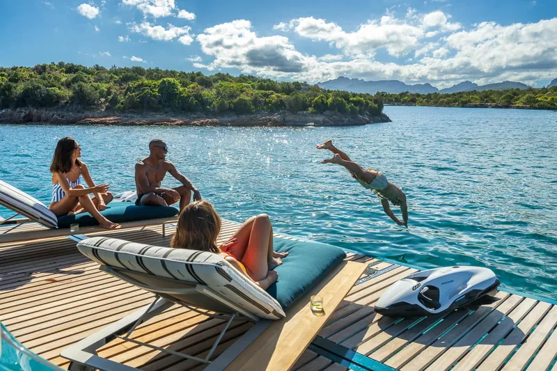Slide: The Image of People relaxing on Lagoon Eighty 2 yacht, 2026, with one diving into the sea. - 15