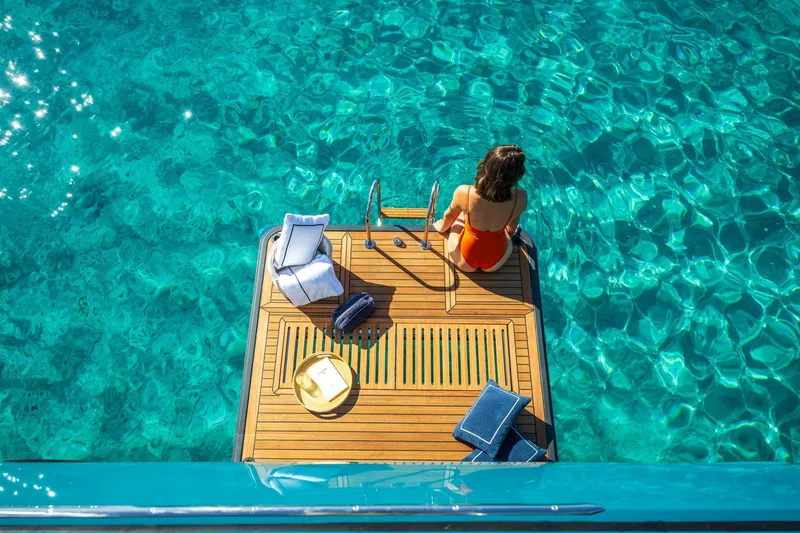 Slide: The Image of Woman relaxing on Lagoon Eighty 2 yacht platform, surrounded by clear turquoise water. - 5