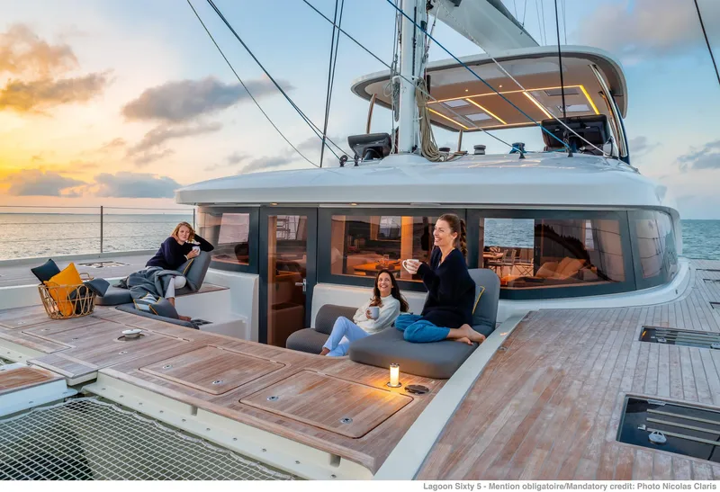 Slide: The Image of Luxurious 2025 Lagoon SIXTY 5 yacht with people relaxing on deck at sunset. - 2