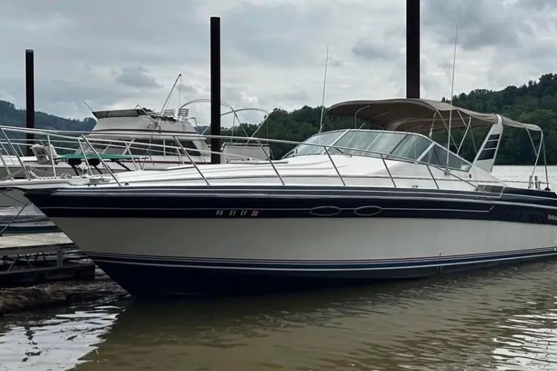 Slide: The Image of 1987 Wellcraft 3400 Gran Sport boat docked on a calm river under cloudy skies. - 3