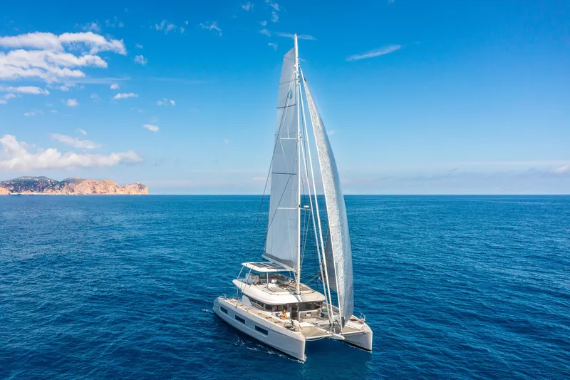 Slide: The Image of 2025 Lagoon 60 catamaran sailing on open sea under clear blue sky. - 2
