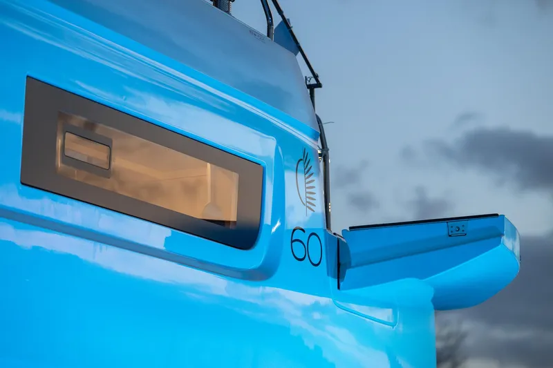 Slide: The Image of 2025 Lagoon 60 yacht, vibrant blue exterior, sleek design, modern window, evening sky backdrop. - 8