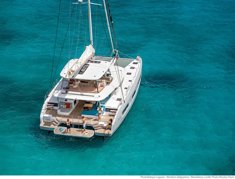 Slide: The Image of 2025 Lagoon 55 yacht on turquoise water, featuring spacious deck and modern design. - 2