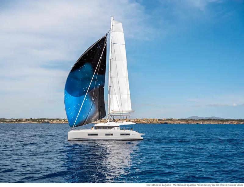 Slide: The Image of 2025 Lagoon 55 sailing yacht with a striking blue and black sail on open water. - 5
