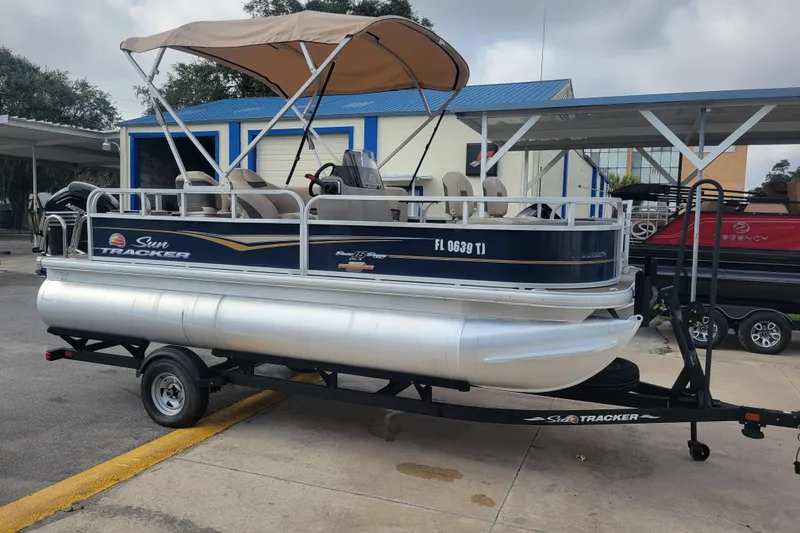 The Image of 2023 Sun Tracker Bass Buggy 18 DLX pontoon boat on trailer, parked outdoors. - 1