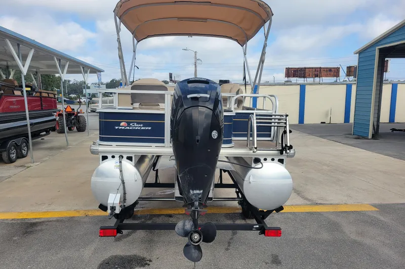 Slide: The Image of 2023 Sun Tracker Bass Buggy 18 DLX pontoon boat with outboard motor, parked at marina. - 3