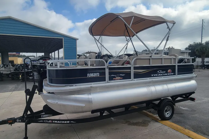 Slide: The Image of 2023 Sun Tracker Bass Buggy 18 DLX pontoon boat on trailer, parked outdoors. - 5