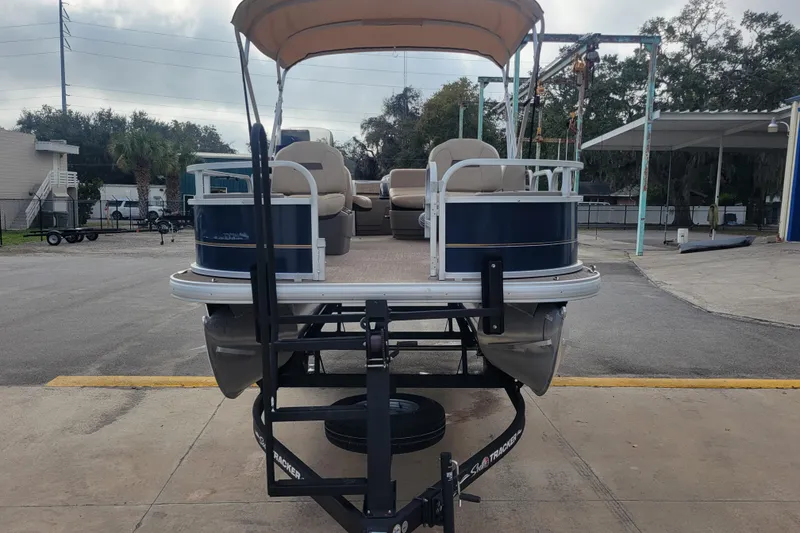 Slide: The Image of 2023 Sun Tracker Bass Buggy 18 DLX pontoon boat on trailer, parked outdoors. - 6